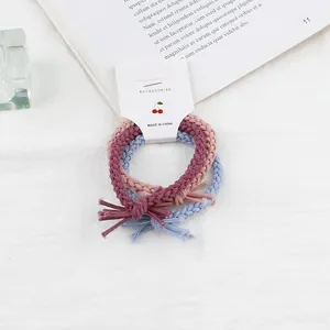 Detail of twisted woven hair ties in pink and blue with a decorative card packaging