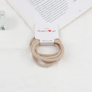 Set of 5 elastic hair ties in nude and beige tones on a white textured background