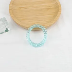 Dettaglio ravvicinato di un elastico a spirale azzurro su panno bianco con vassoio in legno
