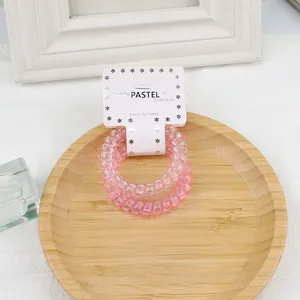 Gros plan de deux chouchous spirales roses présentés sur une carte papier décorative