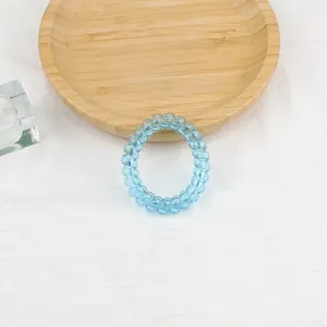 Elastico per capelli a spirale blu trasparente su vassoio in legno e sfondo di lino
