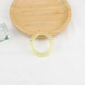 Vista dall'alto di un elastico a spirale giallo trasparente su un vassoio di legno