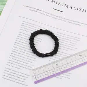 Close-up of black elastic hair scrunchie with soft pleats and smooth fabric texture