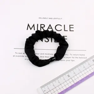 Elastic black fabric scrunchie with oval bead detail on display card with ruler