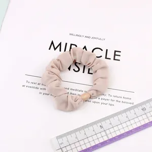Beige elastic ice silk scrunchie with round bead detail shown with a measuring ruler