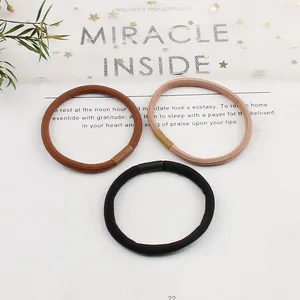 Detail of high-elasticity braided hair ties in black, brown, and beige on a clean background