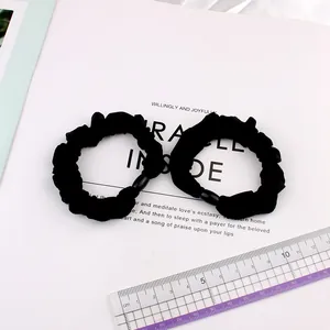 Two black ice silk scrunchies with black buckles on a white magazine background