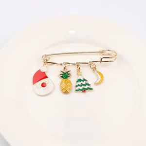 Détail d'une broche épingle à nourrice de Noël avec pères Noël et breloques sapins