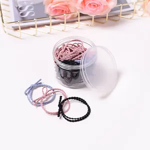Détail d'élastiques à cheveux multicolores avec nœuds dans un bocal cylindrique clair