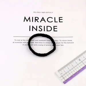 Detail of a thick black elastic hair tie with spiral texture and matte plastic buckle
