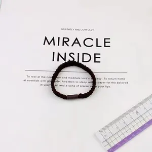 Macro shot of dark brown high-elastic braided hair tie with cylindrical connector and ruler