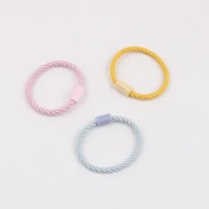 Détail de trois élastiques à cheveux torsadés en rose, jaune et bleu clair