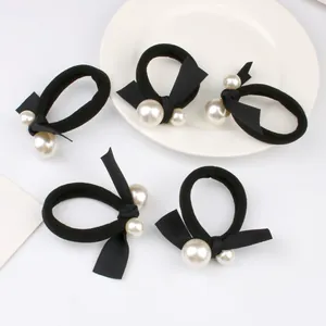 Five black elastic hair ties with fabric bows and decorative white pearls on white background