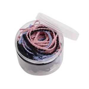 Ensemble d'élastiques à cheveux tressés noirs, roses et bleus dans un pot de rangement