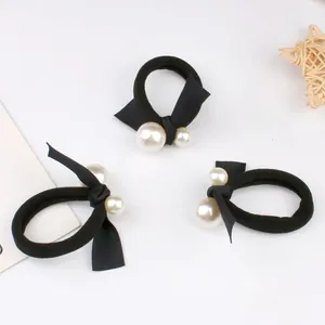 Three black elastic hair ties with silk bows and white pearls on a clean white background