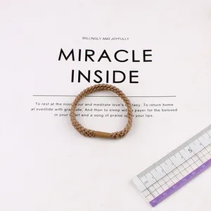 Detailed view of brown braided elastic hair tie with sizing ruler on white card