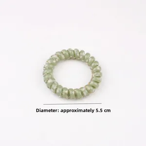 Detail showing a 5.5cm diameter light green polka dot spiral telephone cord hair tie