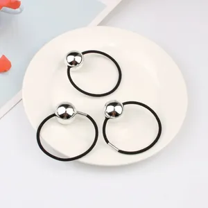 Three minimalist black hair ties with large polished silver metallic spheres on a white tray