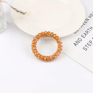 Detail of orange spiral hair tie with white heart pattern on a decorative tray