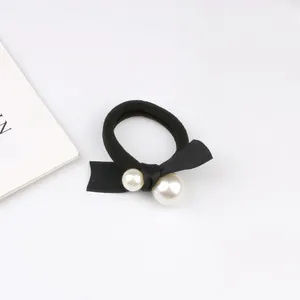 Detail of high-elastic black hair tie featuring a satin bow and two faux pearls