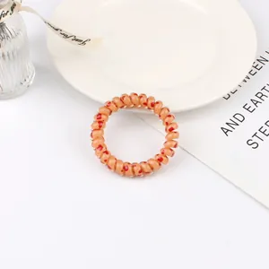Close-up of spiral phone cord hair tie in light orange with red heart patterns