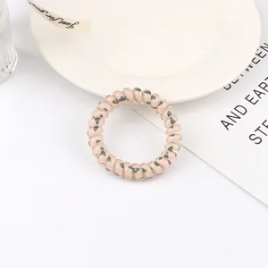 Detail of a pink translucent spiral hair tie with black heart patterns on a white tray