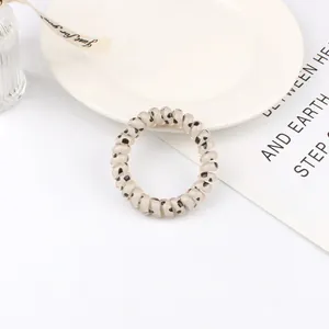 Detailed view of cream spiral hair tie with black heart patterns in a lifestyle setting