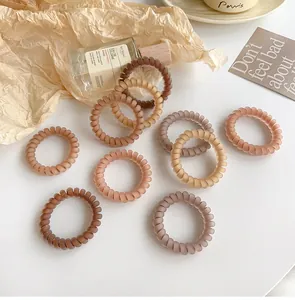 Close-up of 10 matte brown spiral hair ties on white background with decorative props