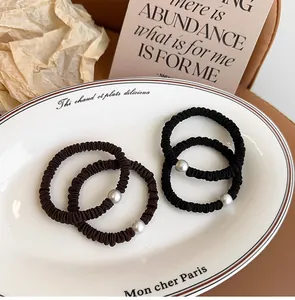 Detalle de gomas de pelo de alta elasticidad con perlas en negro y marrón sobre una bandeja
