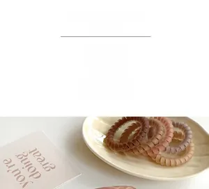 Set of 4 matte coffee-toned spiral hair ties in a ceramic dish with decorative card