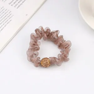 Detail of champagne mesh scrunchie with crystal-encrusted gold bead and soft pleats