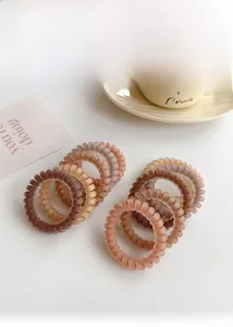 Detail of coffee-toned spiral hair ties with matte finish and high elasticity properties