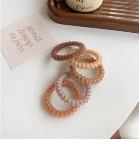 Close-up of five matte spiral hair ties in earthy brown tones on a ceramic tray