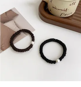 Primer plano de coleteros elásticos marrones y negros con elegantes detalles de perlas