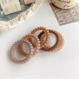 Close-up of four matte spiral hair ties in earth tones on a rustic decorative setup