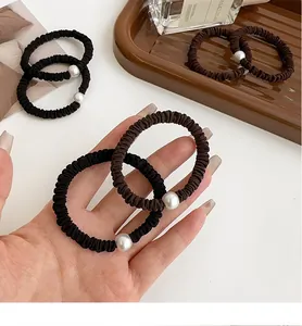 Detalle de gomas para el pelo de tela elástica con elegantes perlas blancas