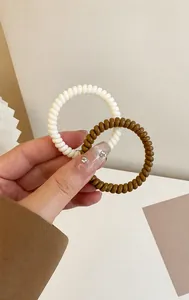 Nahaufnahme von hochelastischen Telefonkabel-Haargummis in Creme und Dunkelbraun