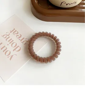 Close-up of matte brown spiral telephone wire hair tie on a decorative tray