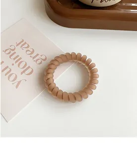Macro detail of brown matte spiral hair tie on textured white background surface