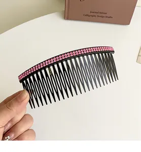 Close-up of black hair comb featuring double rows of pink rhinestones held in hand