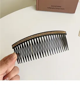 Close-up of elegant black hair comb featuring double rows of gold rhinestones and fine teeth