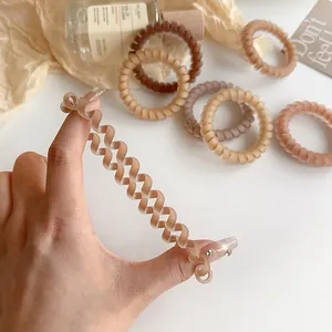 Matte brown spiral hair ties shown stretched to demonstrate high elasticity and grip