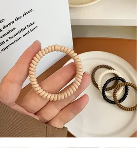 Nahaufnahme flexibler Spiral-Haargummis in neutralen matten Farben für Zöpfe