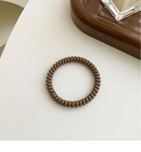 Nahaufnahme eines hochelastischen braunen Spiralhaargummis auf weißem Hintergrund
