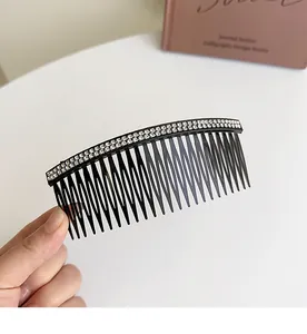 Close-up of a large black hair comb with double rows of sparkling rhinestones held in hand