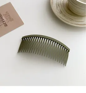 Macro detail of a matte olive green hair comb clip against a minimalist background