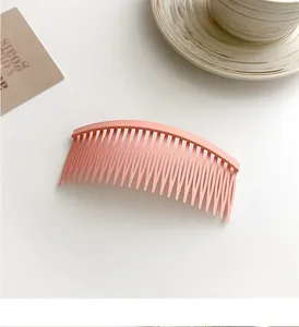 Pink matte curved hair comb for styling and fixing loose hair in a minimal lifestyle setting