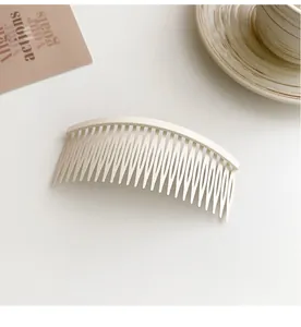 Close-up of matte cream curved hair comb for styling and securing bangs and loose hair