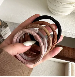 Detail of high-elasticity braided hair ties in neutral earth tones with matte connectors