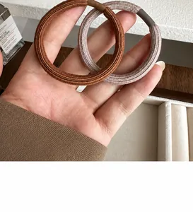 Detail of high-elasticity ribbed hair ties in brown and lavender with leather joint wrap